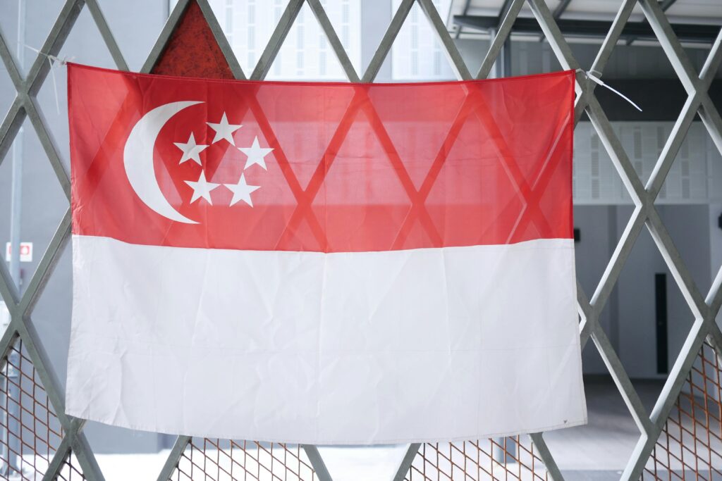 A close-up view of the Singapore flag draped on an indoor metal gate, symbolizing national pride.